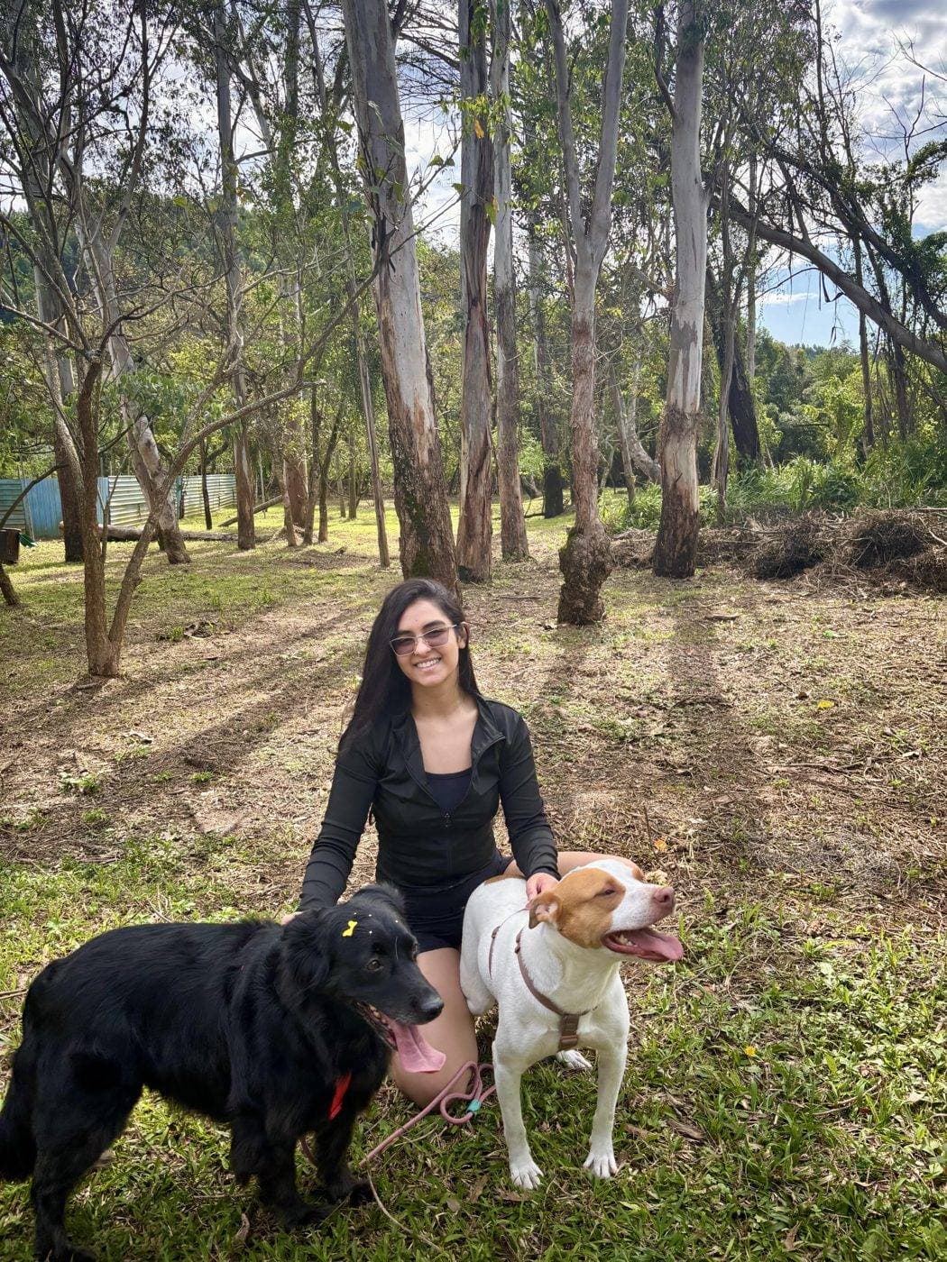 Bianca crouching on the grass with her two dogs, Harry and Pepe