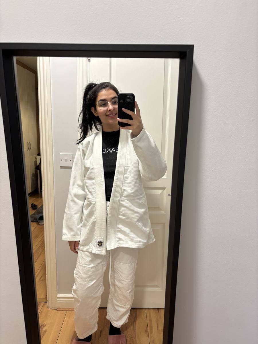 Bianca in a white jiu-jitsu gi, taking a mirror selfie