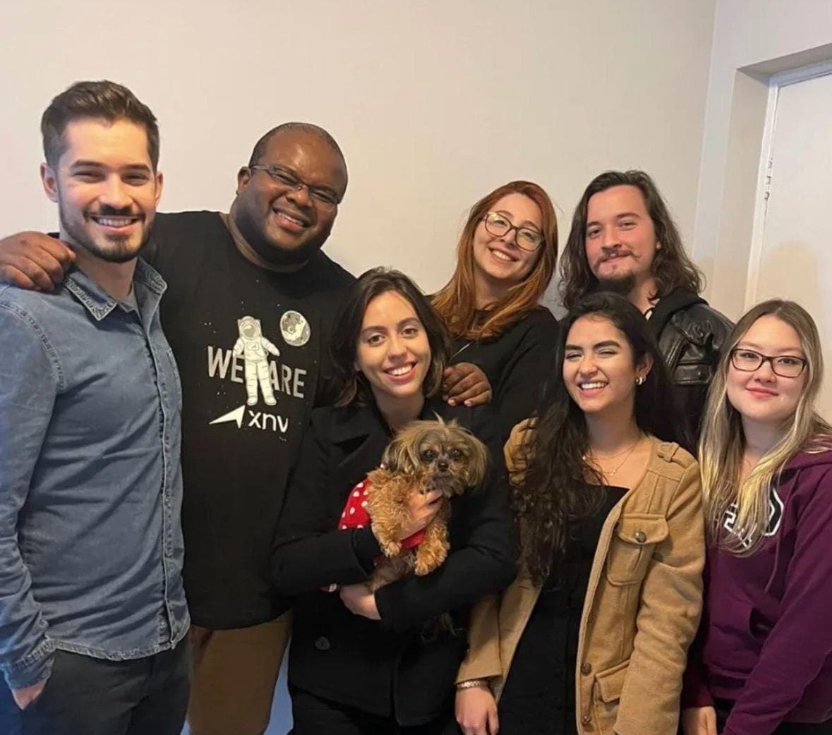 The XNV product team posing together in the office, one of them holding a small dog.
